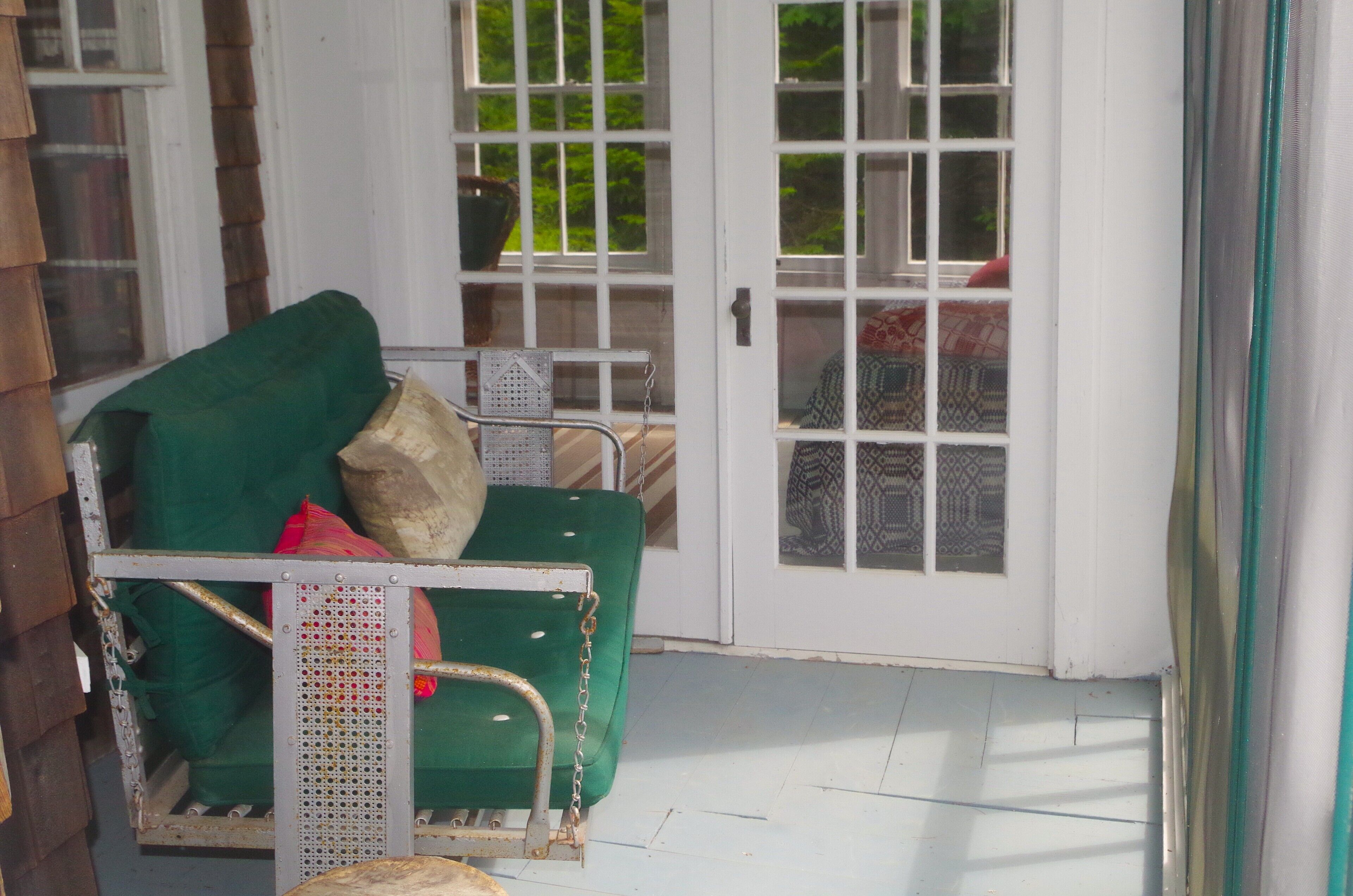A green chair with a metal frame and a cushion, positioned near a white door with glass panels.