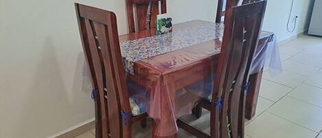 A dining table with four chairs, a tablecloth, and a decorative item on the table.