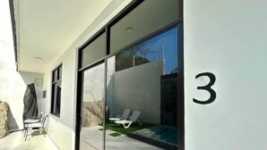 A modern building with large glass windows, a number '3' sign, and a pool area with lounge chairs.