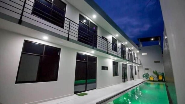 A modern building with a swimming pool, large windows, and a balcony.