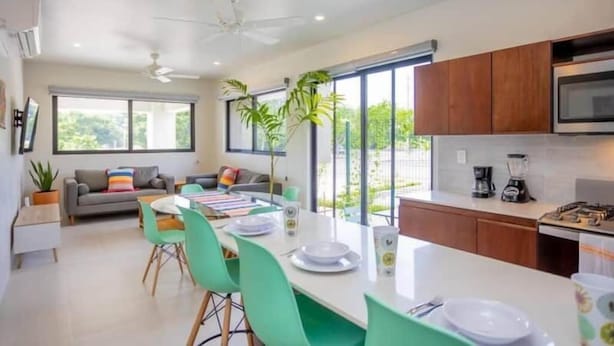 A modern kitchen with a dining area, large windows, and a ceiling fan. - XCAANDA BY YALP (Santa Maria Huatulco)