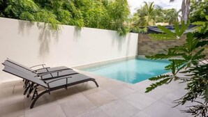 A poolside area with a white wall, a lounge chair, and a tiled floor. - XCAANDA BY YALP (Santa Maria Huatulco)
