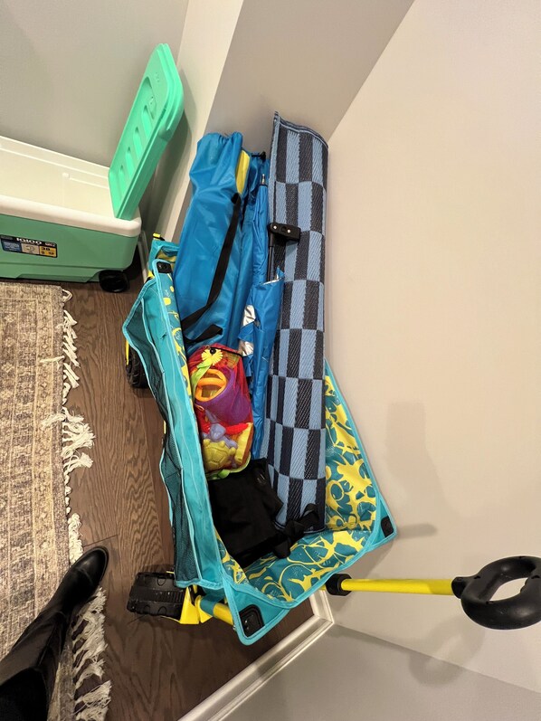 Une valise avec une poignée jaune et un motif bleu et jaune, contenant un sac en filet rouge et jaune, un sac noir et un sac à carreaux.