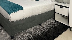 A modern bedroom with a bed, a nightstand, a lamp, and a window with blinds. - 36 On Blougom (Midrand)
