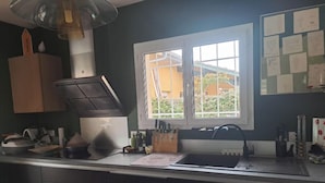 A kitchen with dark cabinets, a window, and a sink. - Jolie maison avec piscine (La Teste-de-Buch)