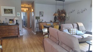 A living room with a sofa, a dining table, and a kitchen area. - Jolie maison avec piscine (La Teste-de-Buch)