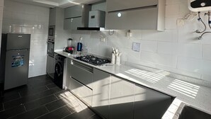 A modern kitchen with stainless steel appliances, a built-in oven, and a dishwasher. - Live, work,& chill in style—4BR Apartment in Central VI (Lagos)