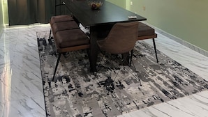 A modern dining room with a marble floor, a dark wooden table, and brown upholstered chairs. - Live, work,& chill in style—4BR Apartment in Central VI (Lagos)