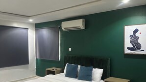 A bedroom with a bed, nightstands, an air conditioning unit, and a painting on the wall. - Live, work,& chill in style—4BR Apartment in Central VI (Lagos)