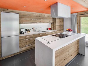 Eine moderne Küche mit einer zentralen Kochinsel, eingebauten Geräten und einer Wand in Holzoptik.