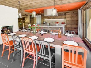 Ein moderner Essbereich mit einem langen Tisch, gedeckt für sechs Personen, umgeben von orangefarbenen und grauen Stühlen.