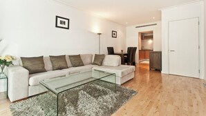 A modern living room with a sectional sofa, a glass coffee table, and a dining area with chairs.