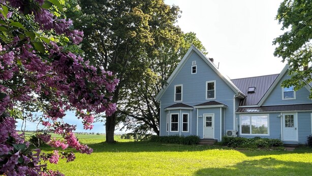 A two-story house with a large lawn and a tree with pink flowers. - 
Bridge View near Confederation Bridge and Beaches (Borden-Carleton)