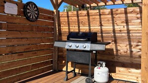 A wooden deck with a grill and propane tank, a dartboard, and a sign reading 'Bridge View'. - 
Bridge View near Confederation Bridge and Beaches (Borden-Carleton)