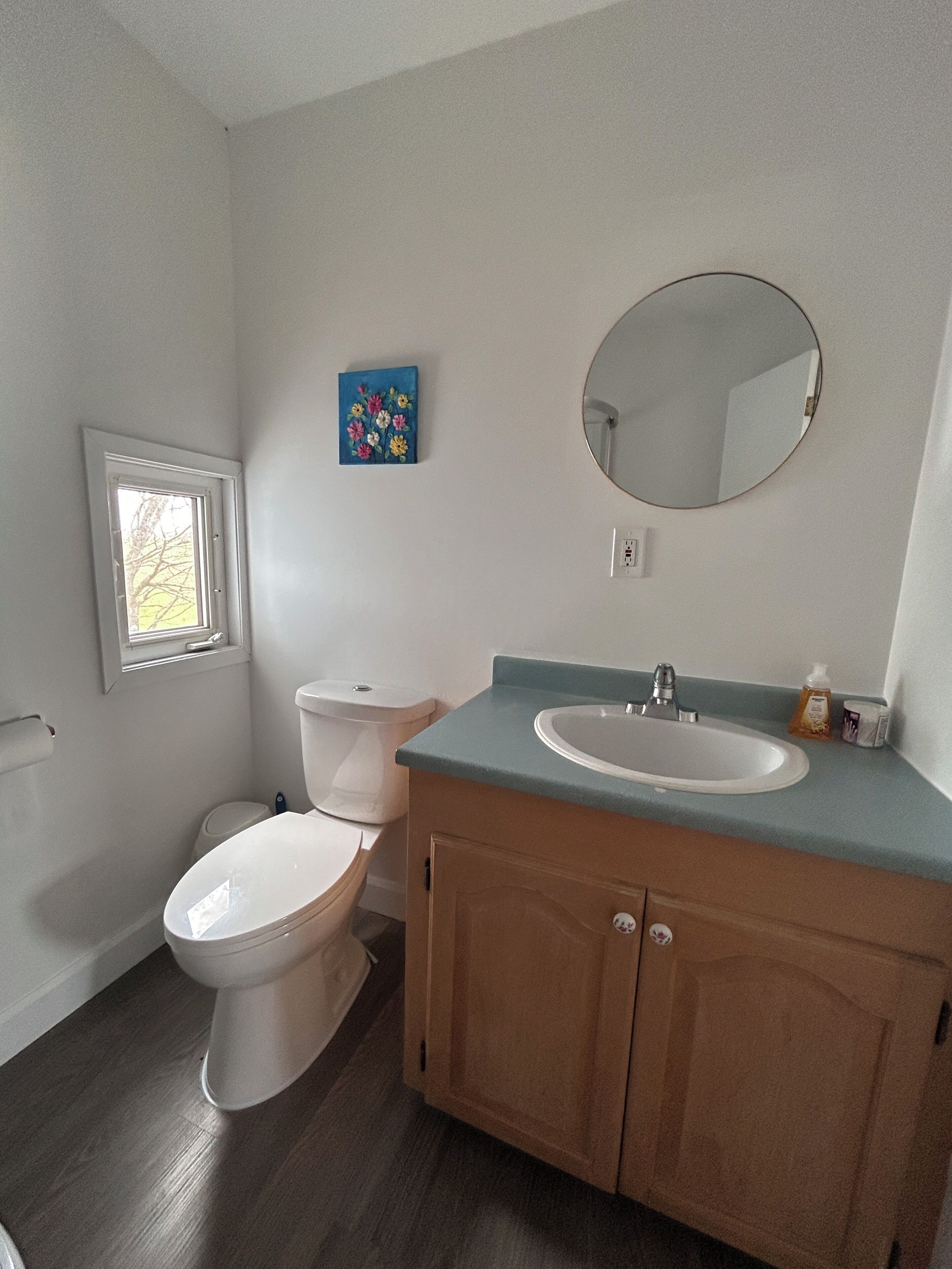 Een badkamer met toilet, wastafel, spiegel en een klein raam.