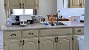 A kitchen with cream-colored cabinets, a stainless steel sink, and various appliances including a toaster and a coffee maker. - 
Bridge View near Confederation Bridge and Beaches (Borden-Carleton)