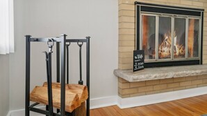 Ein Zimmer mit Kamin, einem Metallgestell mit Holzbrettern und einem Schild, das den Namen und den Preis des Zimmers angibt.