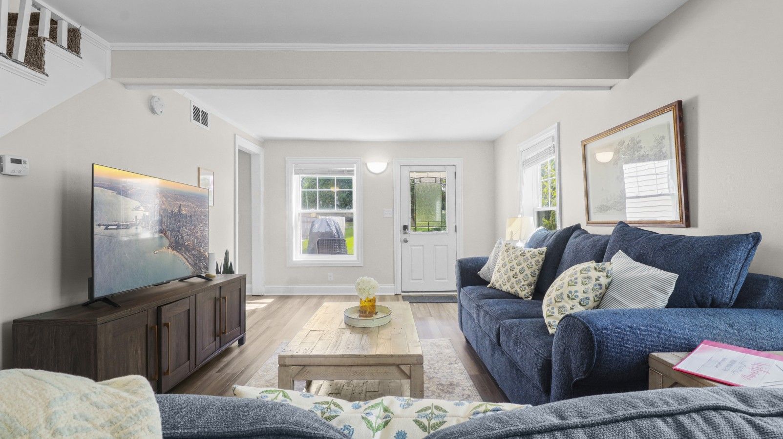 A living room with a television, sofa, coffee table, and a door leading outside.