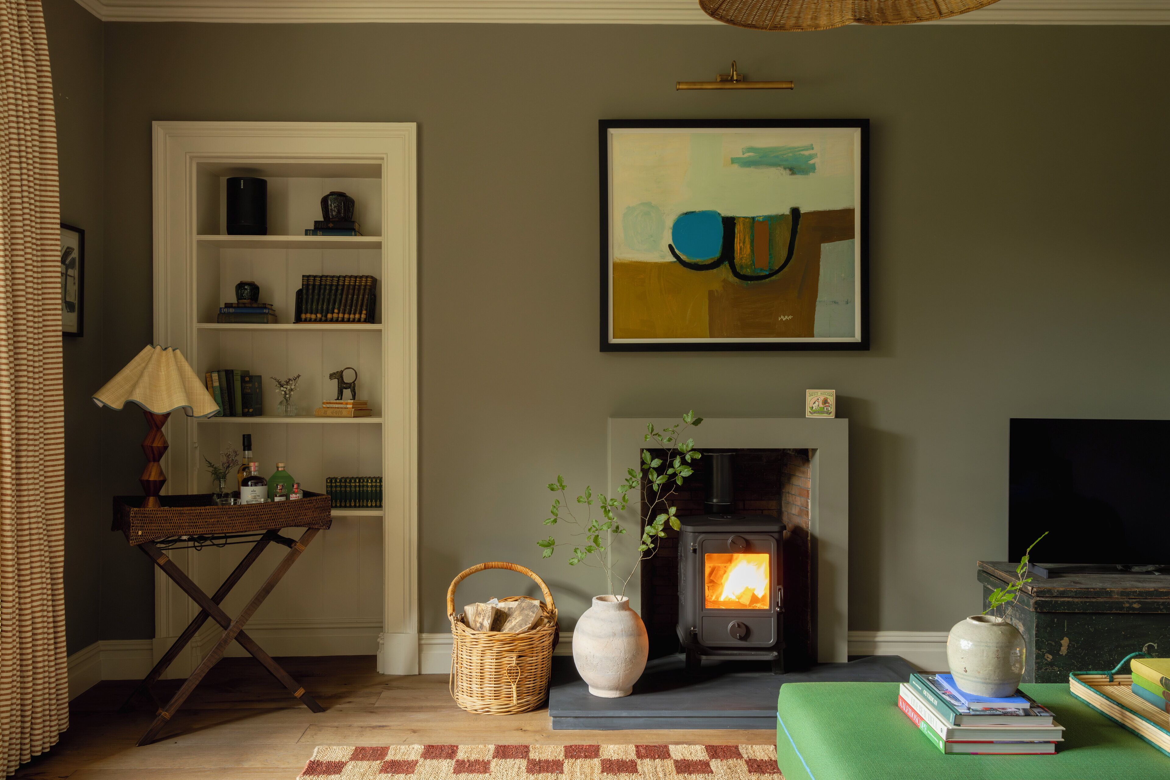 A cozy living room with a fireplace, a bookshelf, and a painting on the wall.