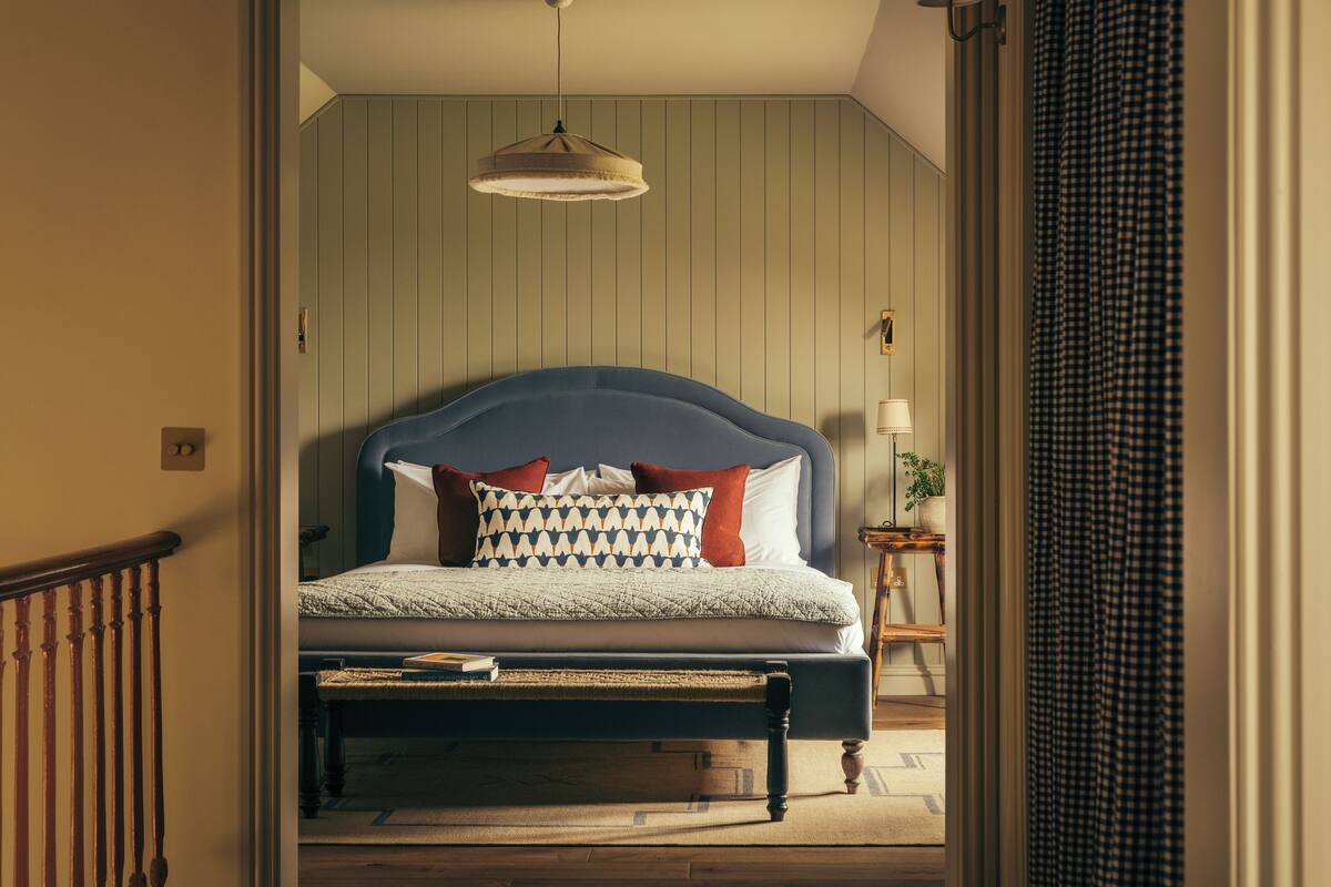 A bedroom with a bed, a bedside table, a lamp, and a hanging light fixture.