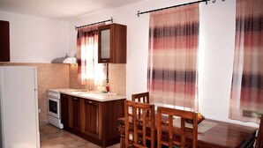 Una cocina con armarios de madera, un refrigerador blanco, una estufa y una mesa de comedor con sillas.