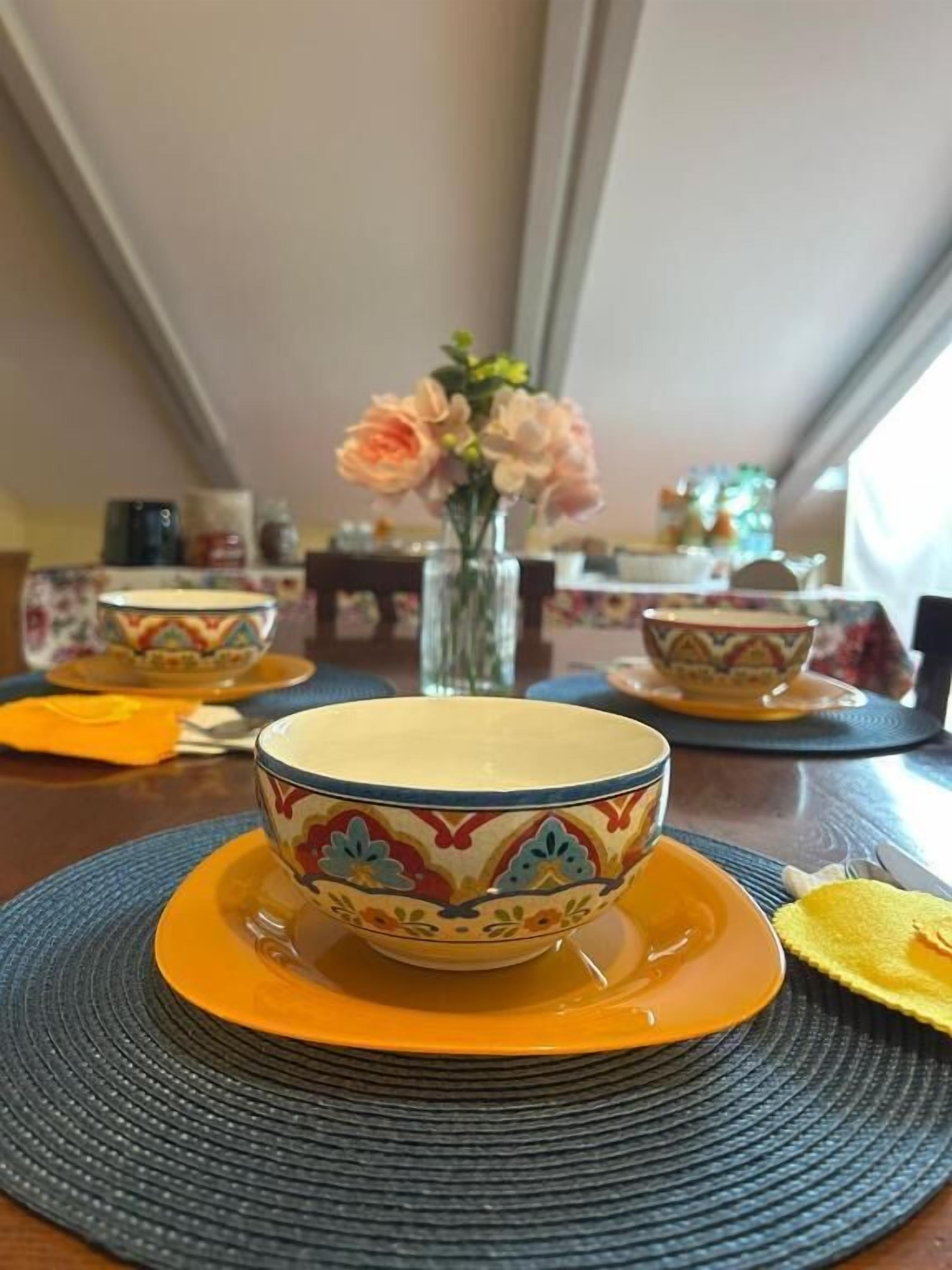 Un tavolo da pranzo con una ciotola e un vaso di fiori.