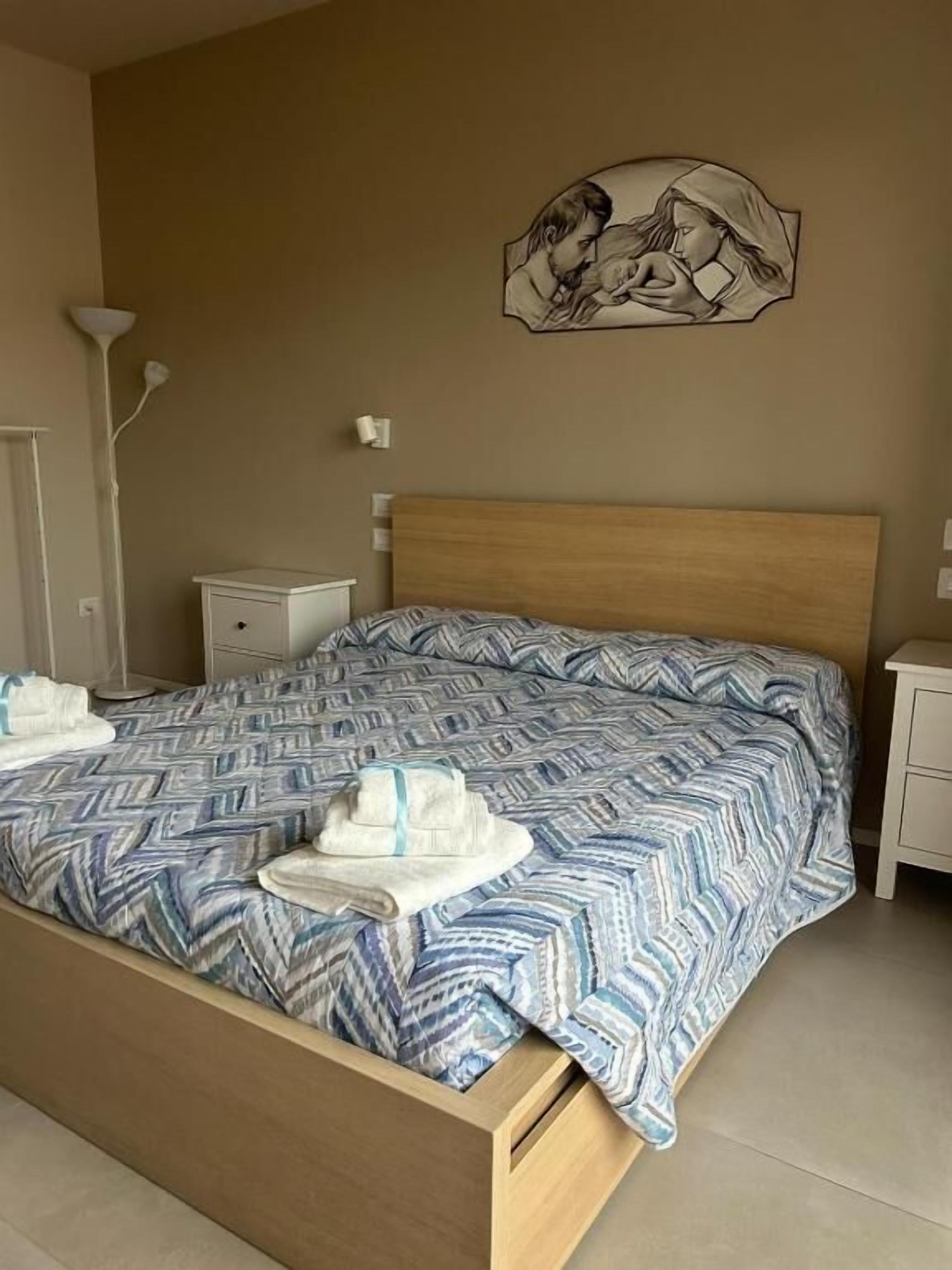 Ein Schlafzimmer mit Bett, Nachttisch, Lampe und Wandbild.