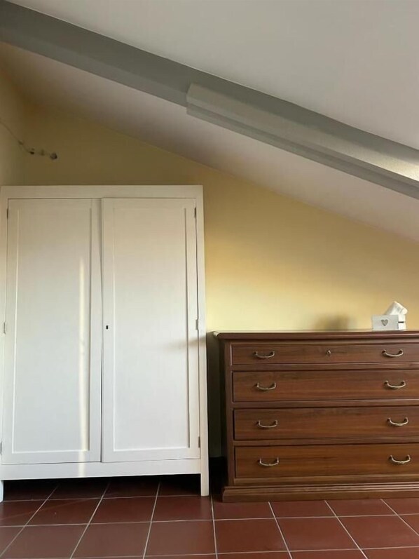 Een kamer met een witte inbouwkast en een houten dressoir met lades.