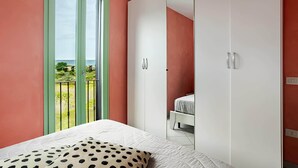 A bedroom with a bed, a wardrobe, and a balcony with a view. - SkyView Apartment in BOSA (Bosa)