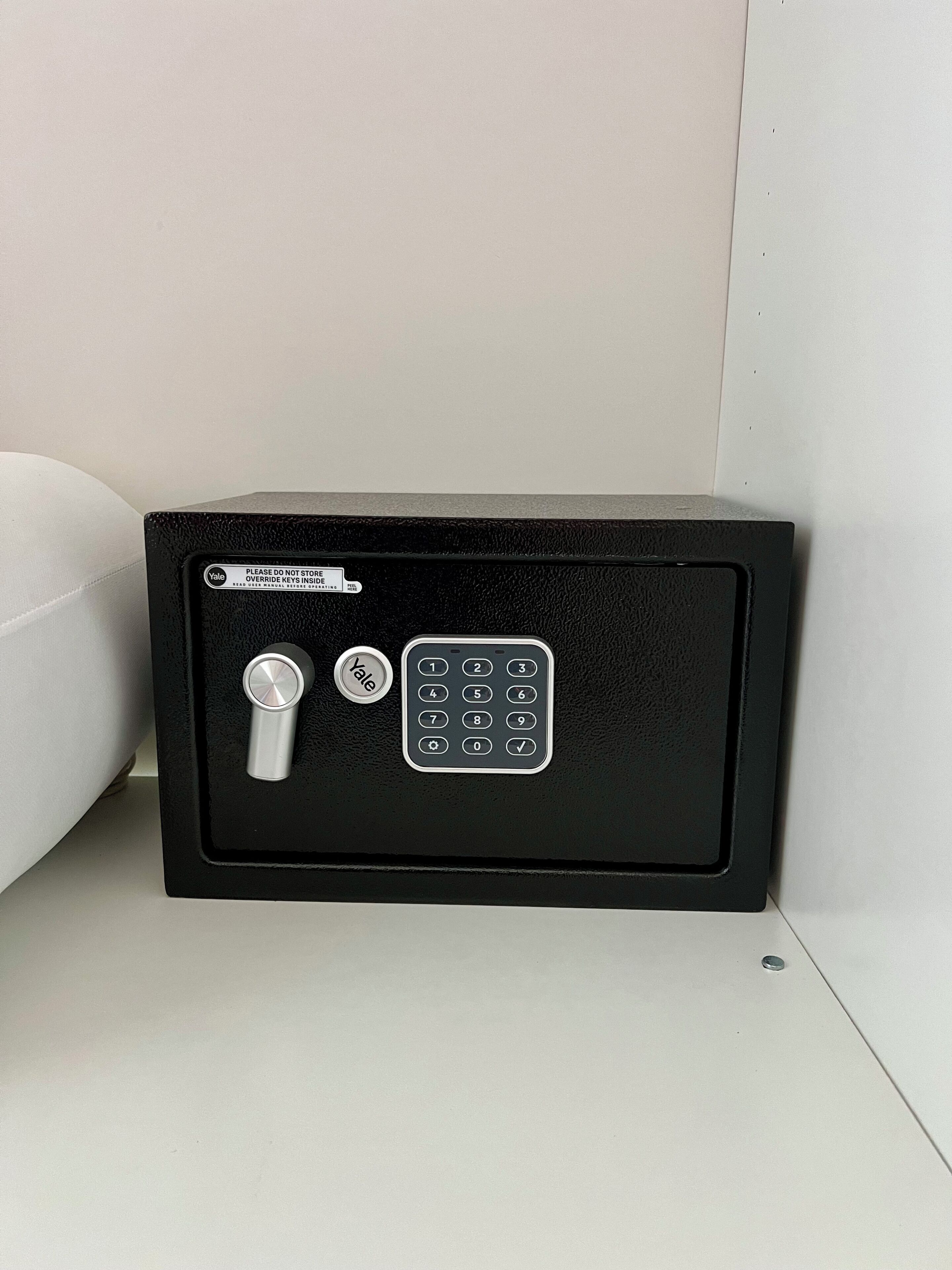 A Yale safe with a combination dial and keypad, placed against a white wall.