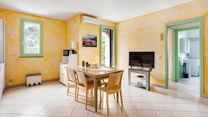 A dining area with a table and chairs, a television, and a view of the outdoors. - SkyView Apartment in BOSA (Bosa)