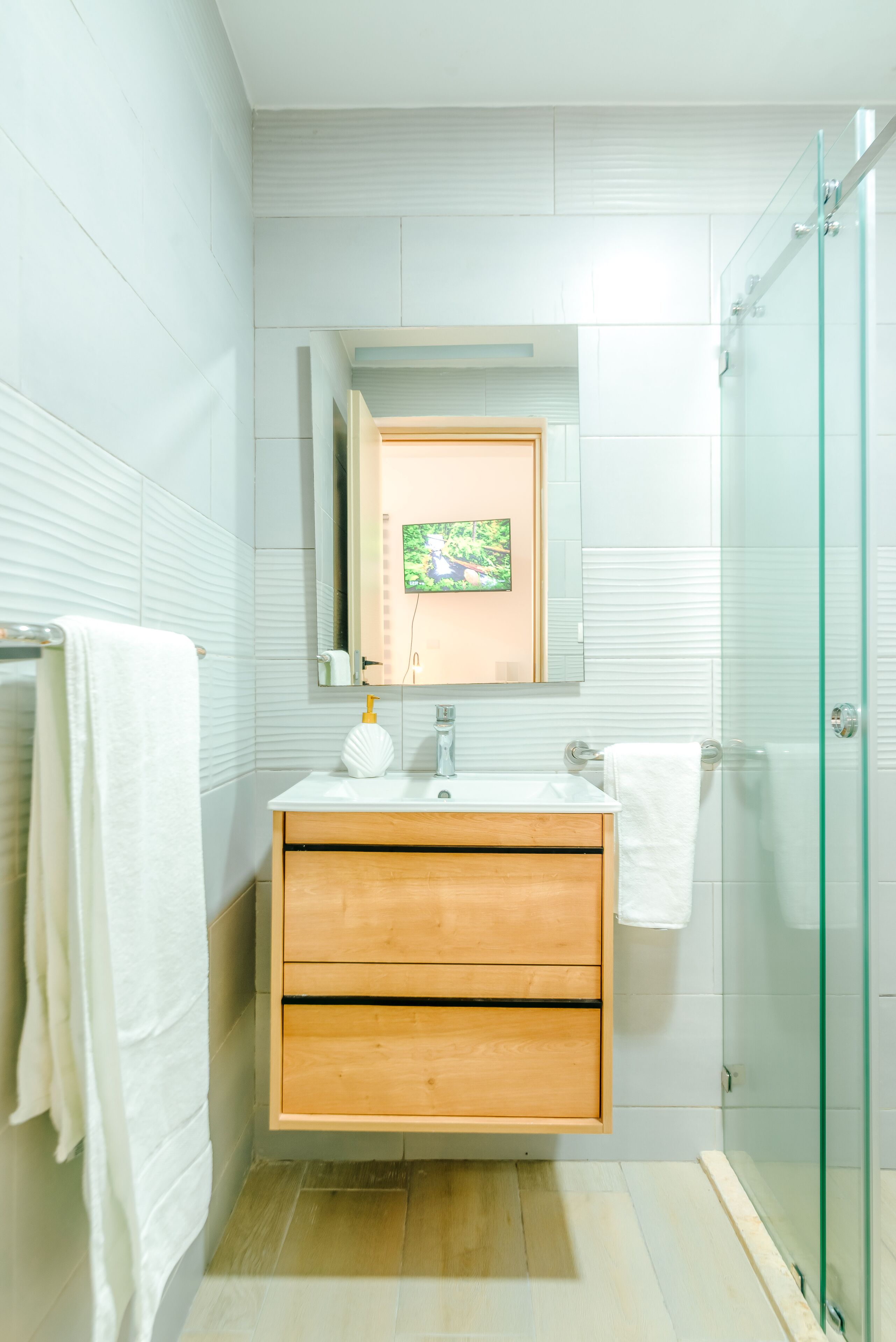 A bathroom with a wooden vanity, a glass shower enclosure, and a framed picture above the mirror.
