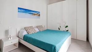 A bedroom with a bed, white nightstand, and a large wardrobe. - Sunset Apartment in BOSA (Bosa)