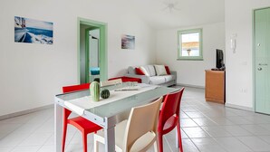A modern living room with a dining area, a sofa, a television, and artwork on the walls. - Sunset Apartment in BOSA (Bosa)