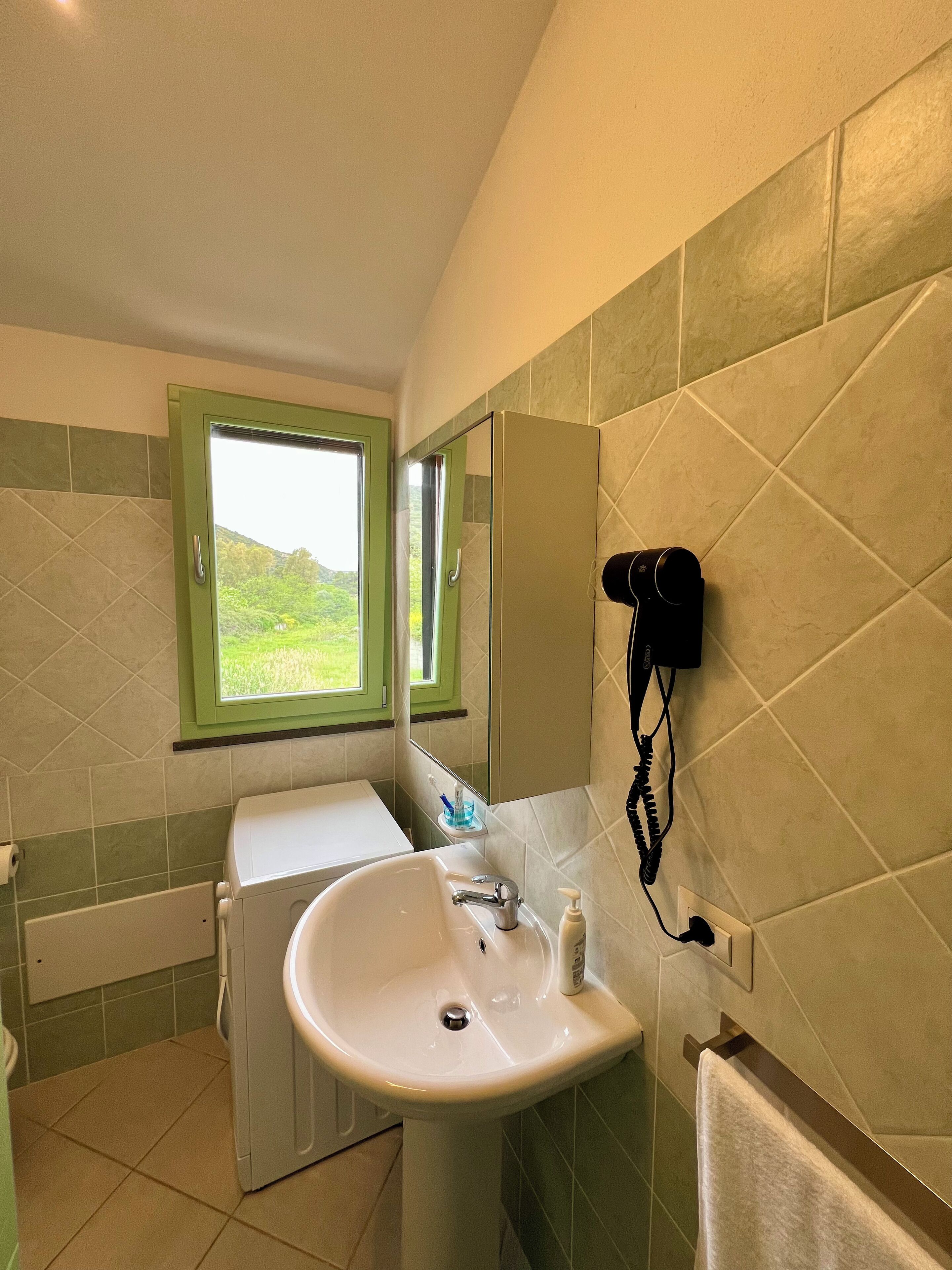 A bathroom with a sink, mirror, and window.