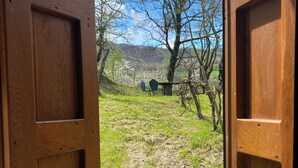 An open wooden door leading to a grassy outdoor area with a table and chairs. - Cà Nova 1590, a charming accommodation in an ancient hamlet (Emilia-Romagna)