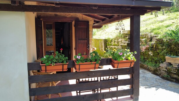 A wooden balcony with potted plants and a stone wall in the background. - Cà Nova 1590, a charming accommodation in an ancient hamlet (Emilia-Romagna)