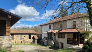 A rustic village with stone buildings, a paved courtyard, and a staircase leading to a second-story entrance. - Cà Nova 1590, a charming accommodation in an ancient hamlet (Emilia-Romagna)