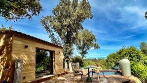 A wooden cabin with a deck, outdoor seating, and a view of the surrounding landscape. - Les Bergeries de Figari (Figari)