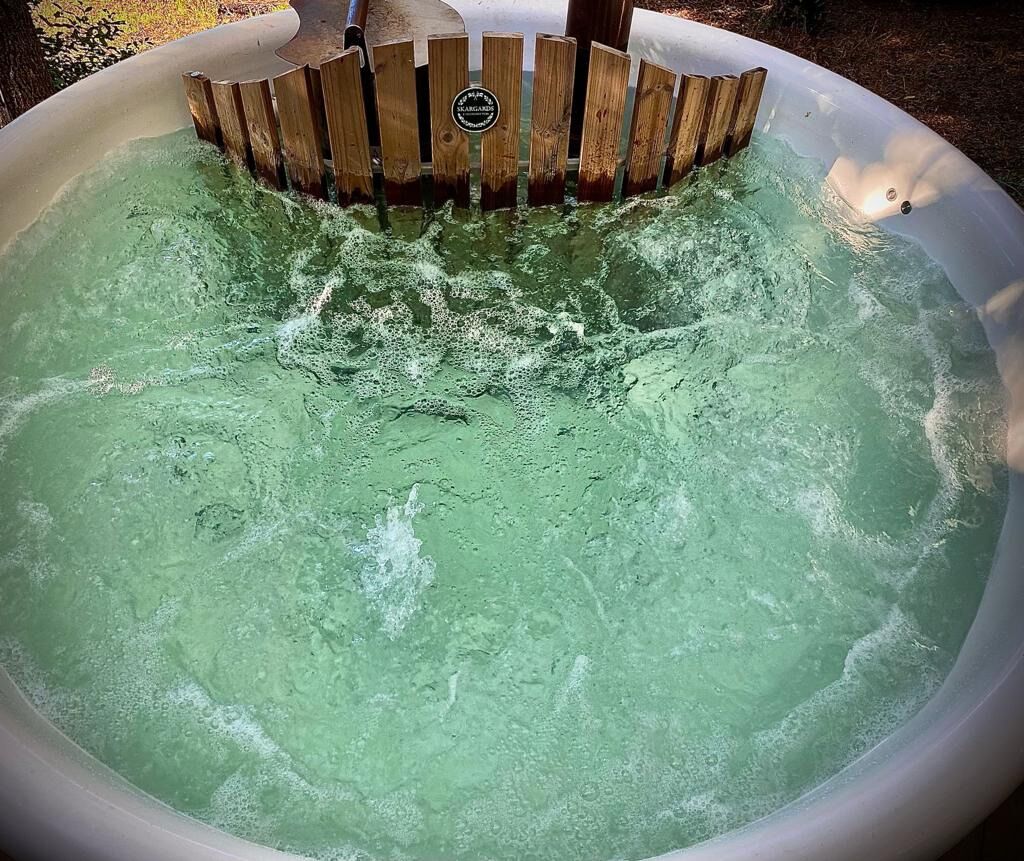 Un bain à remous doté d’un bord en bois et d’un drain en métal.