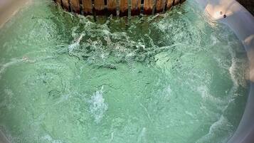 Un bain à remous doté d’un bord en bois et d’un drain en métal.