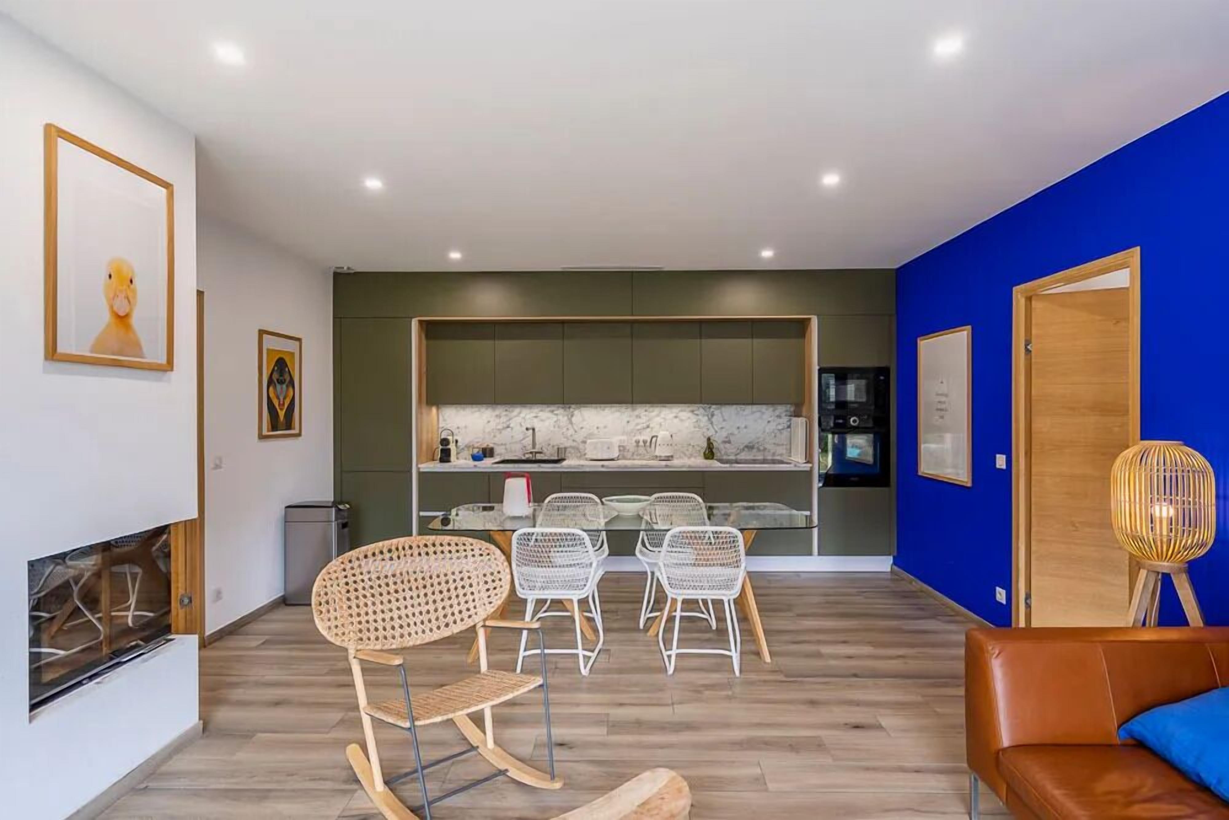 Una sala de estar moderna con comedor, una cocina al fondo y una pared de acento azul.