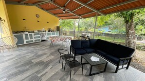 A covered patio with a dining table, chairs, a sofa, and a grill area. - Casa Fofo (San Carlos)