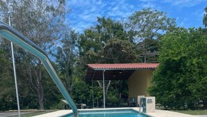 A swimming pool with a metal handrail, surrounded by a concrete deck and trees. - Casa Fofo (San Carlos)