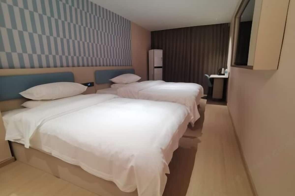 A hotel room with two beds, a checkered wall pattern, a mirror, and a desk with a chair.