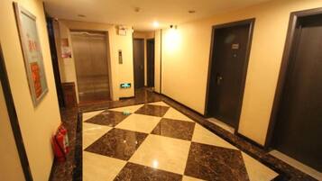 Un pasillo de hotel con piso a cuadros, puertas y un ascensor.