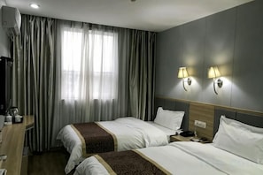 Une chambre d’hôtel avec deux lits, un bureau avec une lampe et une fenêtre avec des rideaux.