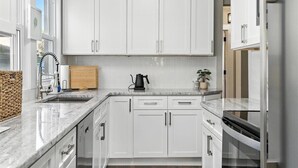A modern kitchen with white cabinets, a marble countertop, a kettle, and a potted plant. - Your Summer HQ!  Ditch the Hotel Rooms! Sleeps 11.   Pet-Friendly! (Dayton)