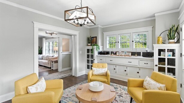 A spacious living room with a round wooden coffee table, two yellow armchairs, and a white sofa. There is a kitchen area with white cabinets and a large window. - Your Summer HQ!  Ditch the Hotel Rooms! Sleeps 11.   Pet-Friendly! (Dayton)
