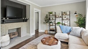 A living room with a fireplace, a television mounted above it, a sofa, and a coffee table. - Your Summer HQ!  Ditch the Hotel Rooms! Sleeps 11.   Pet-Friendly! (Dayton)